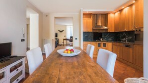 A modern kitchen with wooden cabinets, a marble countertop, and a dining area with a wooden table and white chairs. - A Casa Di Camillo, Nepi, a C (Nepi)
