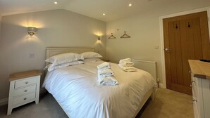 Ein Schlafzimmer mit Bett, Nachttischen, Wandleuchten, einer Heizung und einer Holztür.