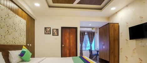A hotel room with a bed, a ceiling fan, a TV, and a wardrobe.