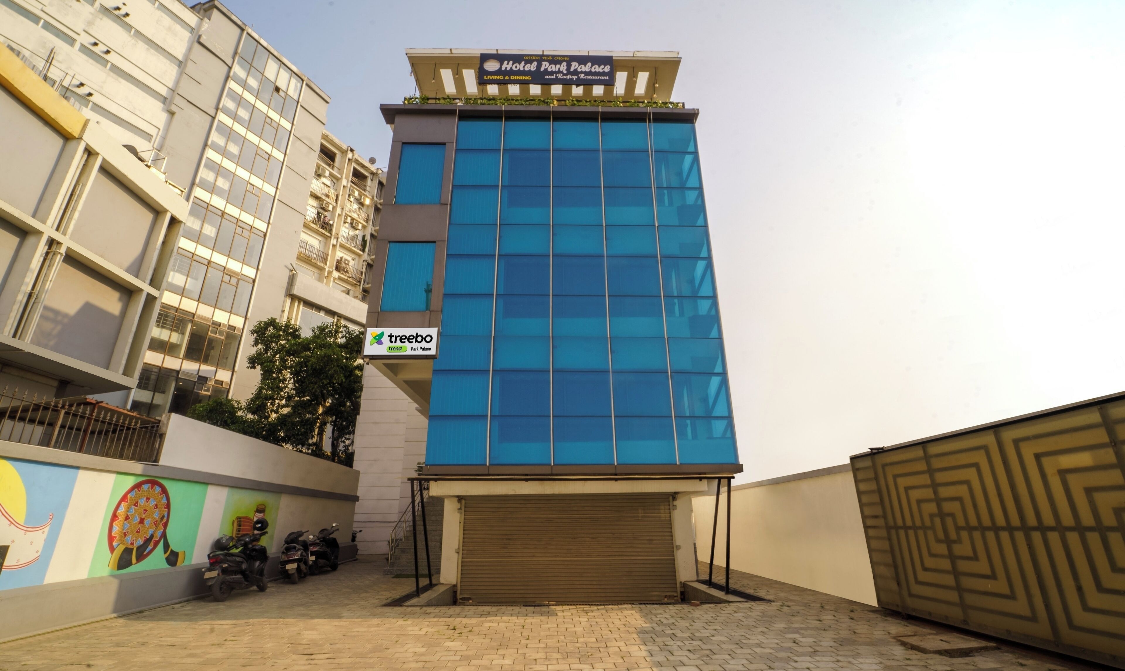 A modern hotel building with a blue facade, a visible entrance, and a sign for 'Hotel Park Palace'.