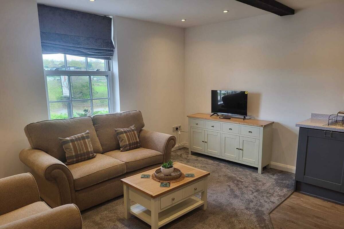 Una sala de estar con sofá, mesa de centro, televisor y mueble.