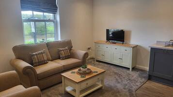 Ein Wohnzimmer mit Sofa, Couchtisch, Fernseher und Schrank.