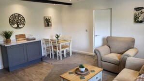 A living room with a dining area, a sofa, a coffee table, and a door.