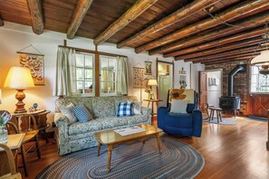 Ein gemütliches Wohnzimmer mit Holzboden, einer Couch, einem blauen Sessel, einem Couchtisch und einem Kamin.