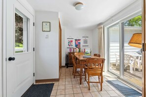 Spiseområde med et træbord og stole, en vægmonteret lampe samt en dør der fører ud til en balkon.