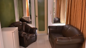 A living room with a brown leather sofa, a white cabinet, and a green door. - Hotel Business (Bogotá)