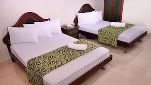Two single beds with wooden headboards, white bedding, and green patterned bedspreads. - Hotel Business (Bogotá)