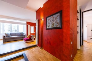 A modern living room with a red accent wall, a grey sofa, and a red and white patterned rug. - Fresh and Trendy Flat at Vomero (Naples)