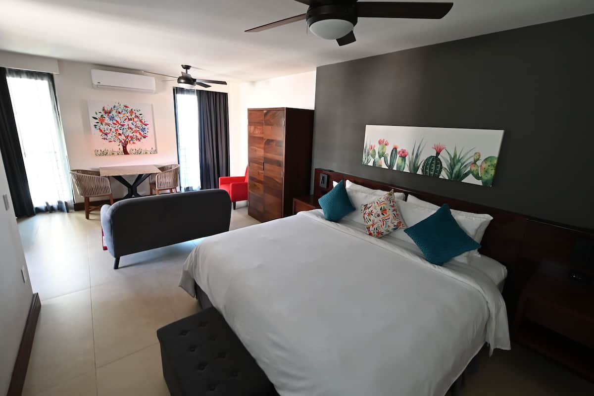 A hotel room with a bed, a desk, a chair, a wardrobe, and a ceiling fan.