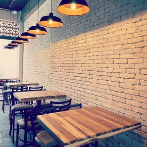 A restaurant interior with brick walls, wooden tables, and hanging pendant lights. - Barrio Vallarta Suites (Puerto Vallarta)
