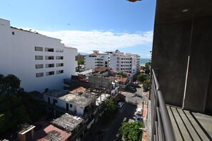 A high-rise building with multiple floors, balconies, and a view of the sea.