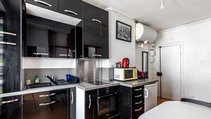 A modern kitchen with black cabinets, stainless steel appliances, and a white countertop. - GuestReady - Parisian haven near attractions (Paris)