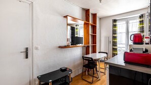 A compact living space with a kitchenette, a dining area, and a small seating area. - GuestReady - Parisian haven near attractions (Paris)