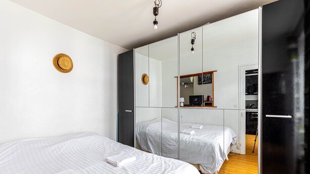 A bedroom with two beds, a wardrobe, a mirror, and a small desk with a chair. - GuestReady - Parisian haven near attractions (Paris)