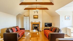 A spacious living room with two sofas, a fireplace, and a television.