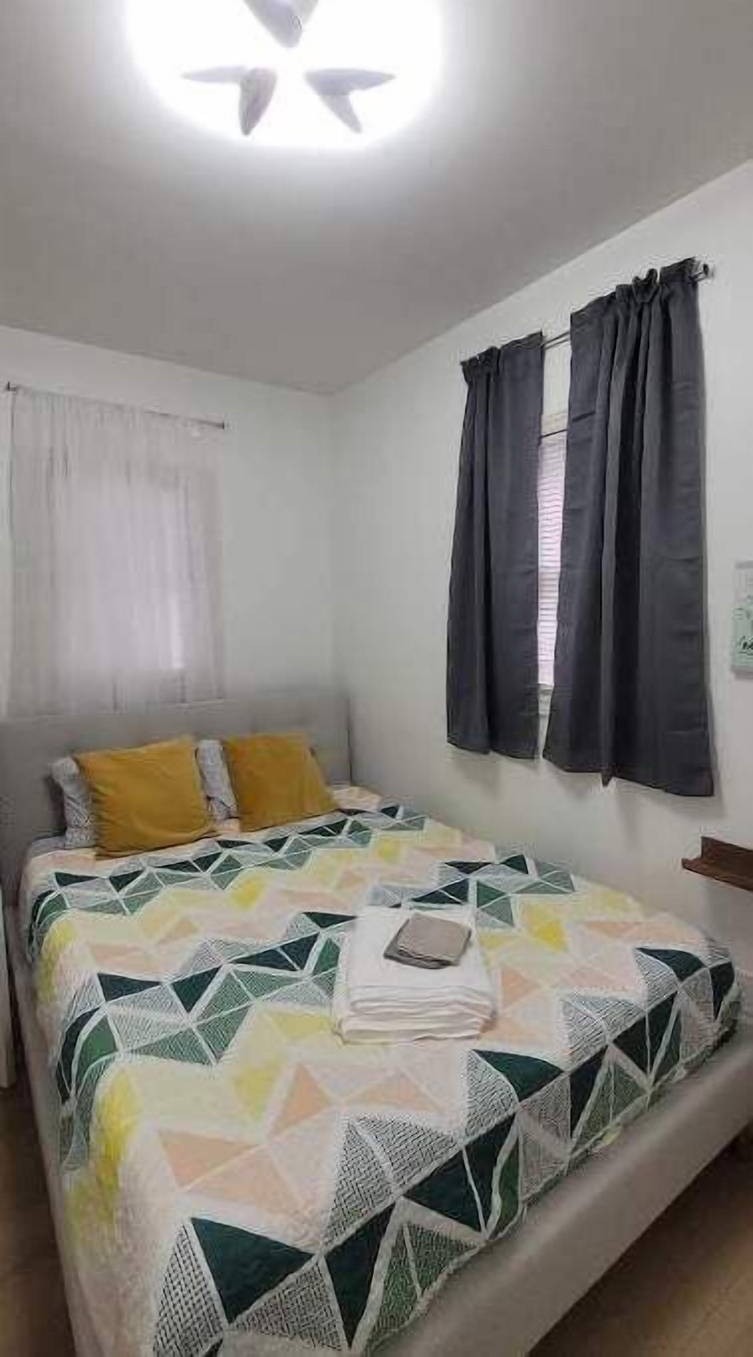 A bedroom with a bed, curtains, and a window.