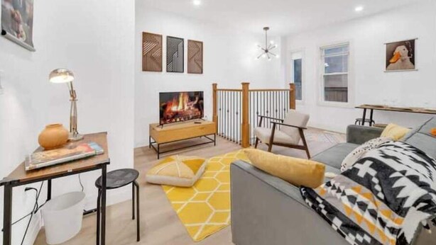 A modern living room with a fireplace, a sofa, a coffee table, and a dining area.