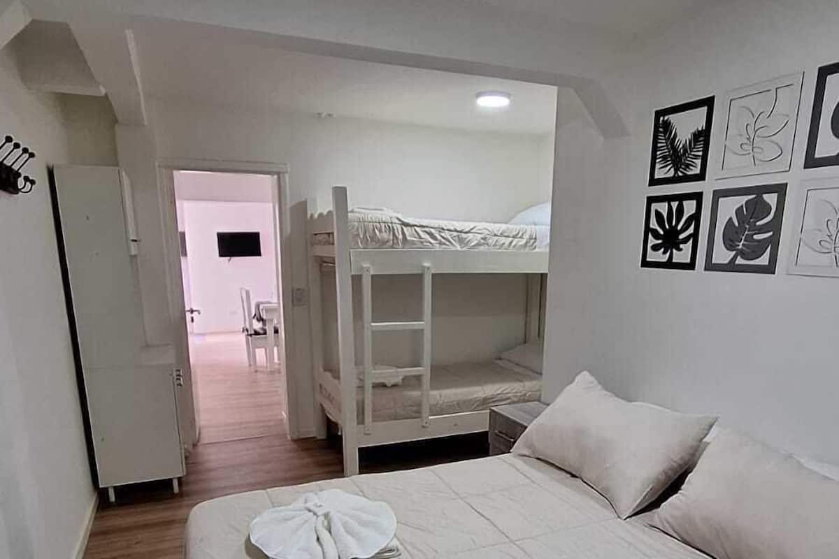 Ein Hotelzimmer mit einem großen Bett, einem Etagenbett und einer Tür zu einem Flur.