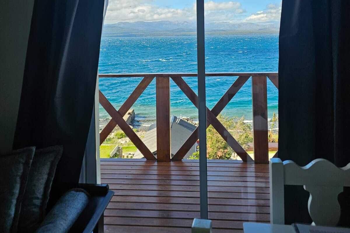 Ein Zimmer mit einer großen Schiebetür und Zugang zu einer Holzterrasse mit Blick auf ein Gewässer.