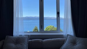 A room with a large window overlooking a body of water and mountains. - Los Dones Departamentos DAT (San Carlos de Bariloche)