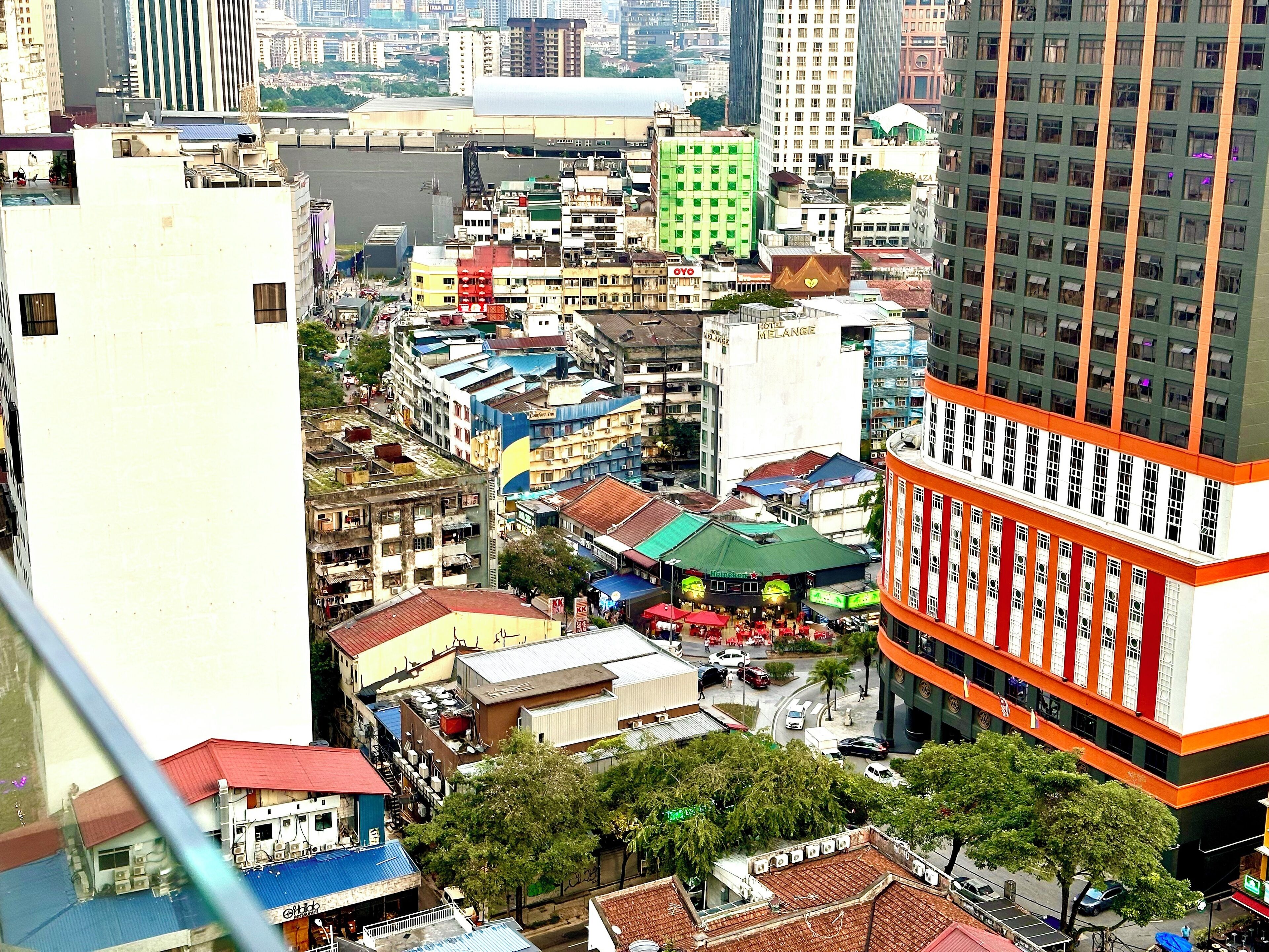 A high-rise hotel with a distinctive orange and white facade, multiple floors, and a central courtyard with a green-roofed building.