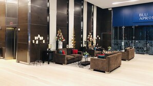 A modern lobby with a seating area, a reception desk, and a large blue sign reading "BLU APROMOT".