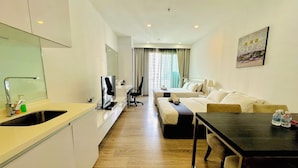 Een hotelkamer met kitchenette, een bank, een bed en een eettafel.