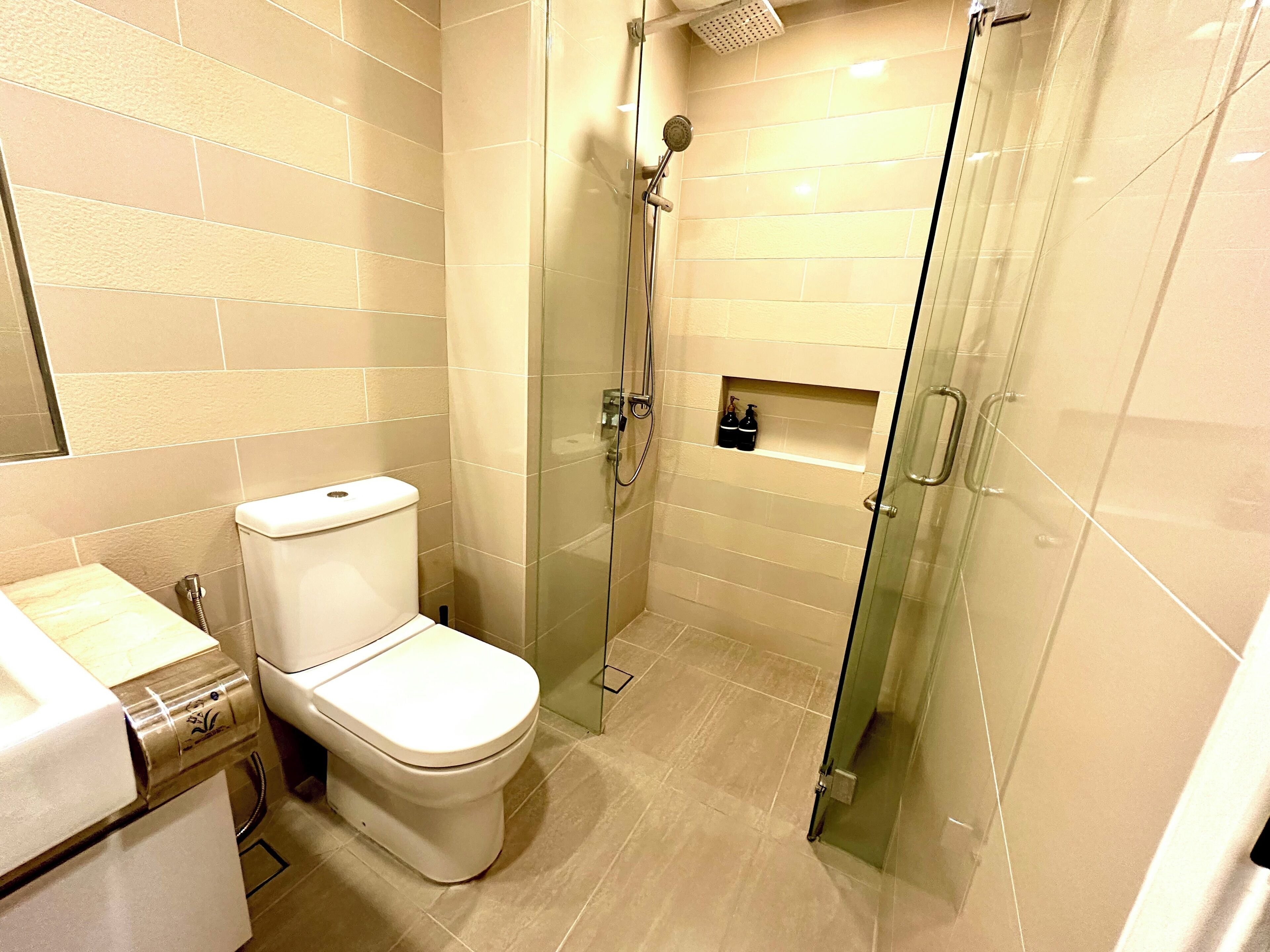 Une salle de bain moderne équipée de toilettes, d’une douche et d’un espace douche vitré.