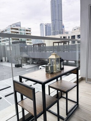 Enjoy the unobstructed city view from this balcony with a table and chair.