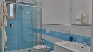 A modern bathroom with a glass shower enclosure, a toilet, a sink, and a mirror. - 1 Bedroom Apartment in Castellammare di Stabia (Castellammare di Stabia)