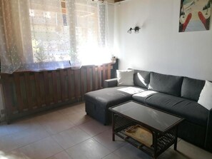 A living room with a sofa, a coffee table, and a window with curtains.