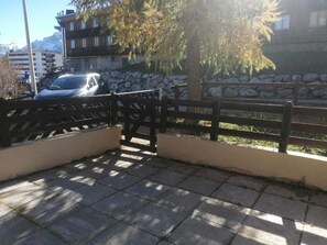 A paved outdoor area with a stone wall and a wooden fence.