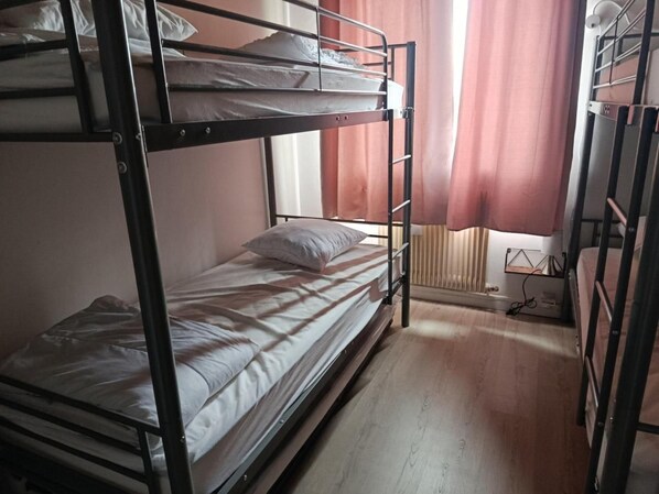 A bunk bed room with a window, a radiator, and a power outlet on the floor.
