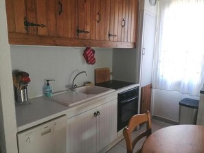 A compact kitchen with wooden cabinets, a Bosch dishwasher, a sink, and a stove.