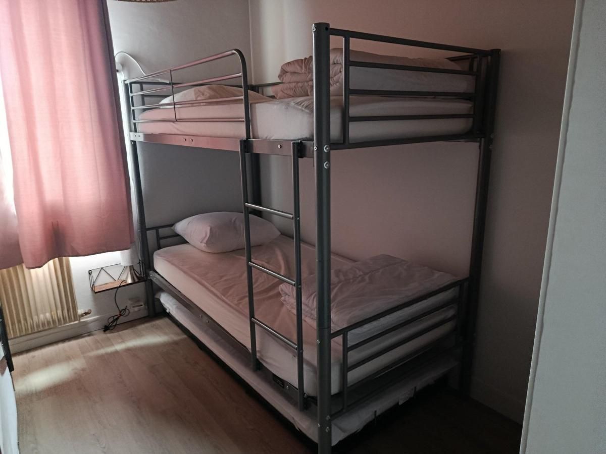 A bunk bed with a metal frame, a window with blinds, and a radiator.
