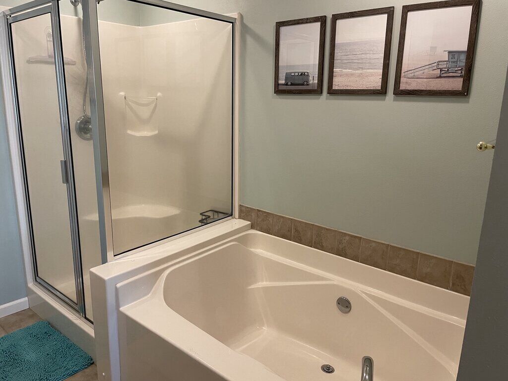 Un baño con ducha a nivel, bañera y tres cuadros enmarcados en la pared.