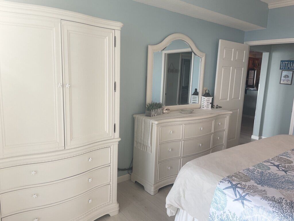 Ein Schlafzimmer mit einem großen Bett, einem Schminktisch, einem Spiegel und einem Kleiderschrank.