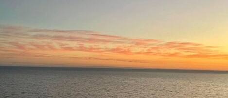 A calm sea at sunset with a clear sky.