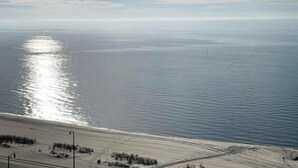 Un paysage côtier avec une plage, une mer calme et un ciel dégagé.