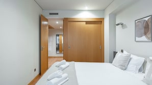 Et hotelværelse med en stor seng, et træskab og et badeværelse, der kan ses gennem en åben dør.