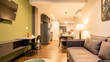 Una sala de estar moderna con un sofá, una televisión y un comedor con una mesa y sillas.