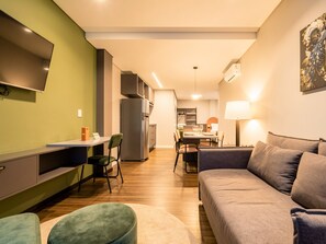 Una sala de estar moderna con un sofá, una televisión y un comedor con una mesa y sillas.