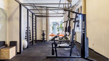 Une salle de sport équipée de matériel d’exercice, d’une barre de traction et d’une fenêtre avec des rideaux.