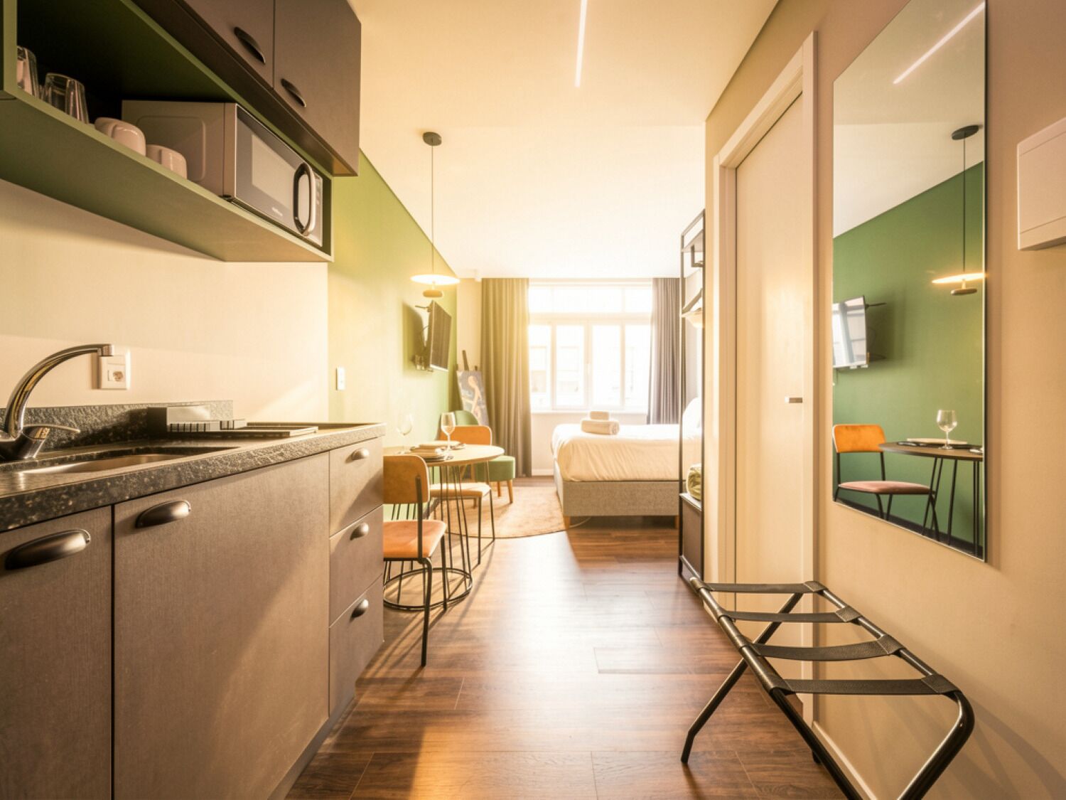 Een compacte hotelkamer met een kitchenette, een eethoek en een bed.