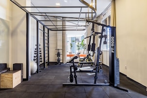 A gym with exercise equipment, a pull-up bar, and a window with curtains.