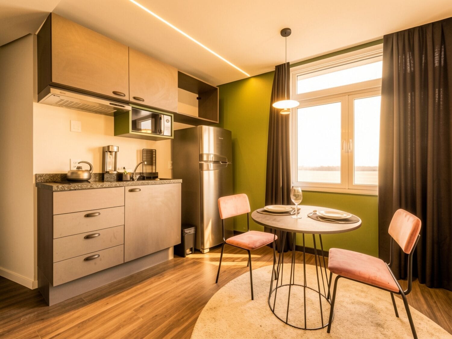 A compact kitchen with modern appliances, a dining area with two chairs, and a view through a window with curtains.