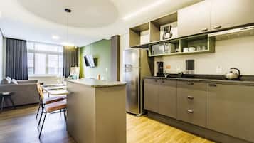 Una cocina moderna con una isla central, electrodomésticos integrados y un comedor con sofá y sillas.