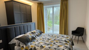 Una camera da letto con un letto, un armadio, una sedia e una finestra con tende.