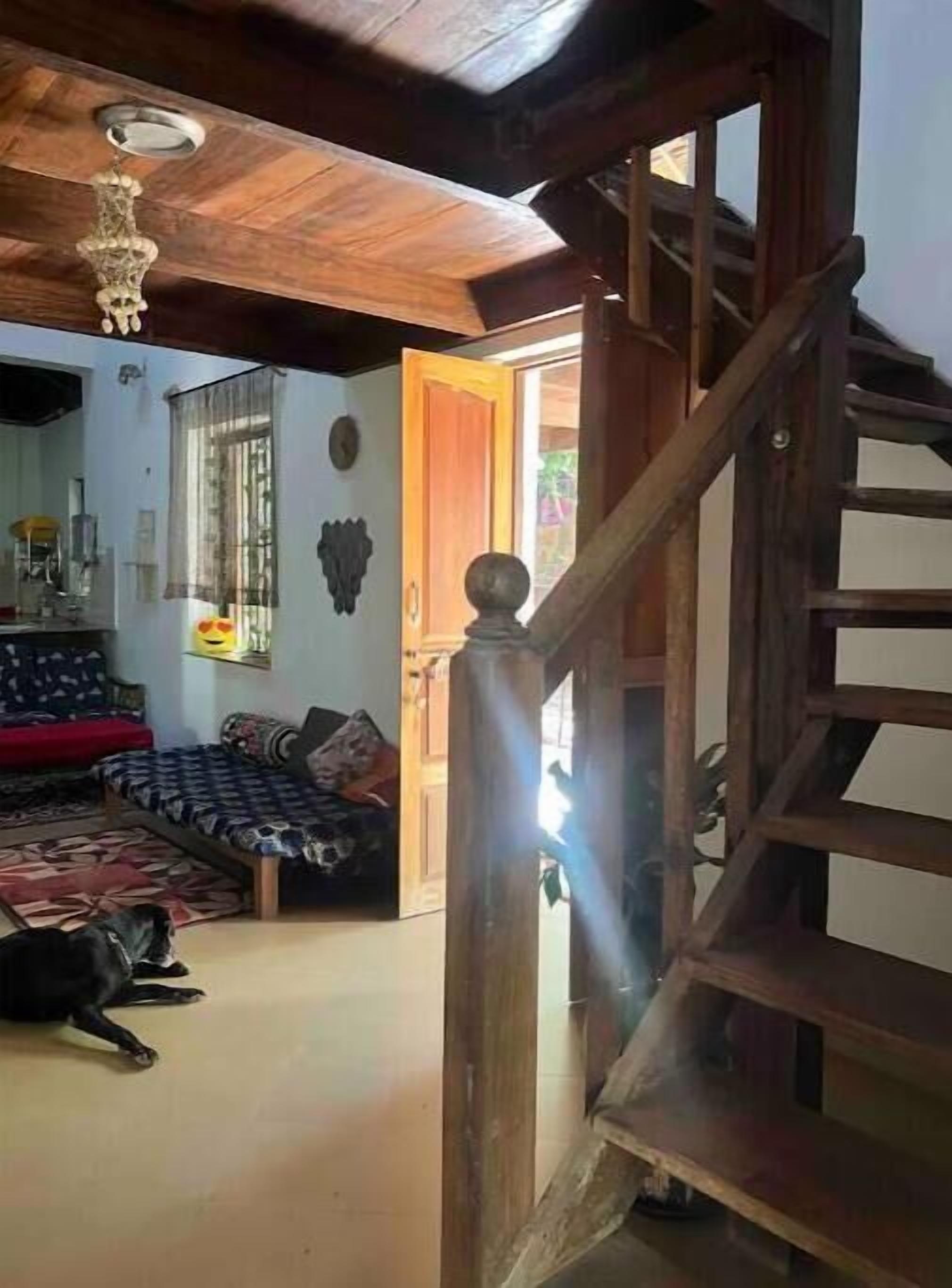 Uma escada de madeira que leva a um quarto com uma cama, uma janela e uma porta.