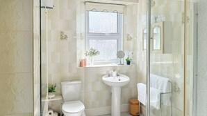 Un baño con inodoro, lavamanos y cabina de ducha de vidrio.
